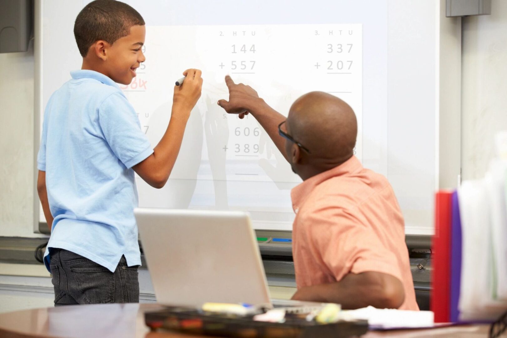 A man and boy are pointing at something on the whiteboard.